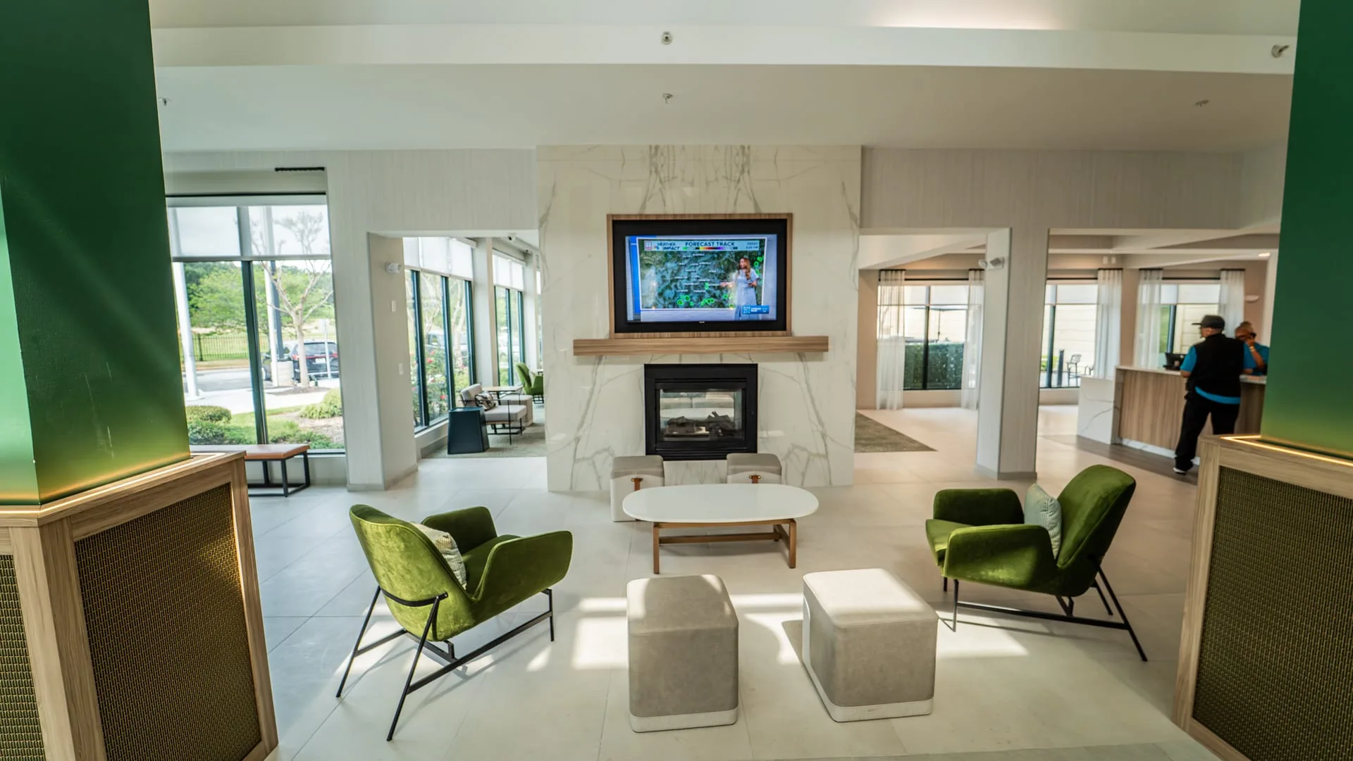 Lobby fireplace and TV wall framed by white veined panels, with seating and decorative column bases